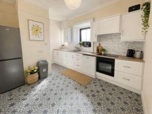 a kitchen with white cabinets and a black refrigerator at The Malting House in Skerries
