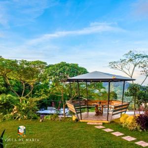 a gazebo in a yard with two benches at Villa de Maria Suites in Binungan