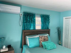 a bedroom with a bed with blue walls and a window at Jubilee Gardens Freeport in Freeport