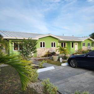 a green house with a car parked in front of it at Jubilee Gardens Freeport in Freeport