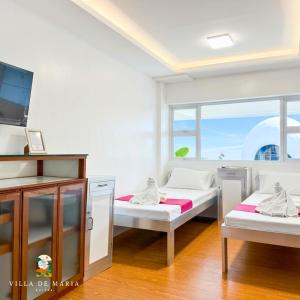 a room with two beds and a tv in it at Villa de Maria Suites in Binungan