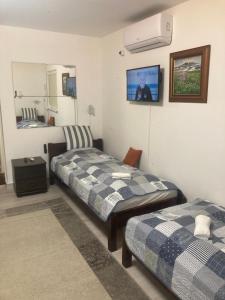 a bedroom with two beds and a tv on the wall at Oázis Apartman in Orfű