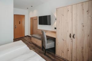 een slaapkamer met een bureau en een tv aan de muur bij Feichter Hotel & Living in Bolzano