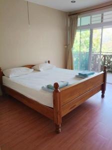 a bed with a wooden frame in a room with a window at Volk resotel in Ban Nong Chaeng