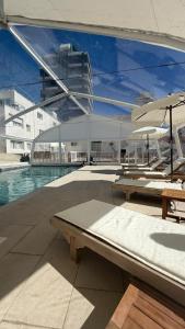 a pool with tables and umbrellas and a building at Hotel Florinda in Punta del Este