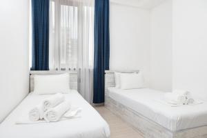 two beds in a white room with towels on them at Bright 2BR Residence Central Yerevan in Yerevan