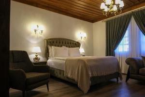 a bedroom with a bed and two chairs and a chandelier at Gülce Köşk Otel & Restaurant in Amasya +81 photos