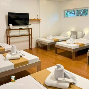a room with four beds and a flat screen tv at Villa de Maria Suites in Binungan