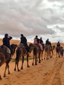 a group of people riding horses in the desert at Auberge camping la tradition in Merzouga