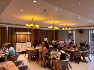 a group of people sitting at tables in a restaurant at SKY PENTA RESIDENCY in Iritti