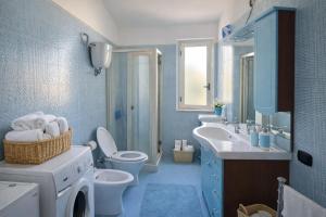 a blue bathroom with a washing machine and a sink at Cala Greca Case Vacanze in Capo Rizzuto +96 photos