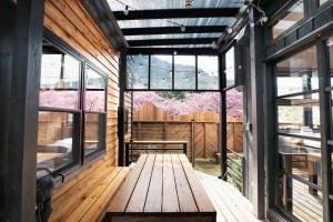 a wooden porch with a bench and windows at Tiny Base The River in Kawazu