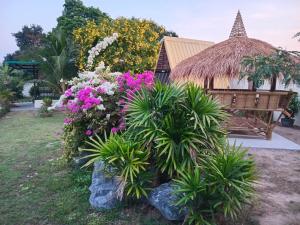 a garden with flowers and a bench and a building at TRANQUILITY Resort in Nong Prue
