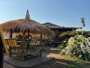 a straw hut with chairs and a table at TRANQUILITY Resort in Nong Prue