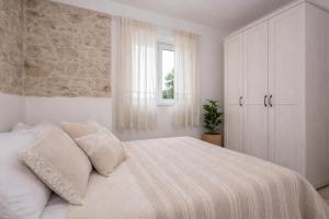 a white bedroom with a bed with pillows and a window at Didovi dvori in Bibinje +99 photos