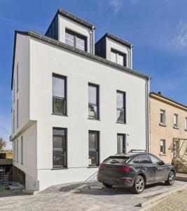 a white building with a car parked in front of it at NEW - Mullerthal Basecamp - Sleeps 6 in Beaufort