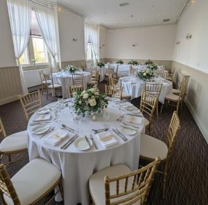 a banquet room with white tables and chairs with flowers at THE YoRK in Morecambe