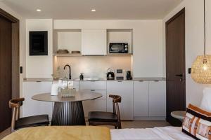 a kitchen with a table and a small kitchen with white cabinets at MonCasa suites in Agios Nikolaos