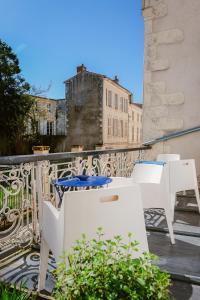 a balcony with white chairs and tables on a balcony at Hotel de La Paix in La Rochelle