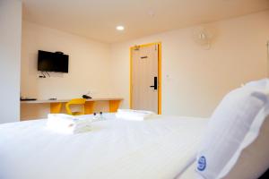 a bedroom with a white bed with a tv on the wall at Global Inn & Suites in Mangalore +17 photos