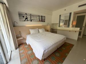 a bedroom with a large white bed and a mirror at New Jimbaran Hotel in Ungasan +2 photos