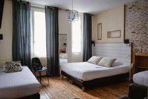 a bedroom with two beds and a chair in it at Hotel de La Paix in La Rochelle