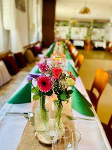 a long table with flowers in vases on it at Gasthaus Bidinger in Schoden
