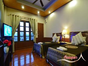 a living room with two beds and a television at บ้านไร่คุณนาย in Ban Sap Bon