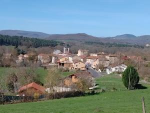 a small village with houses and a green field at L'atelier in Sugères