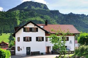 a white house with a mountain in the background at Wohlfühl-Ferienwohnungen Schneider in Bad Hindelang +5 photos