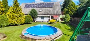a pool in a yard with a house with solar panels at U Boží hory. in Žulová