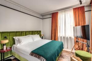 a bedroom with a bed with a green headboard and a television at Hotel Santa Maria Maggiore in Rome