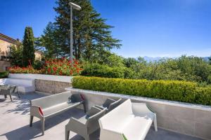 a patio with white chairs and a wall with flowers at Hotiday Sorrento Capo in Sorrento