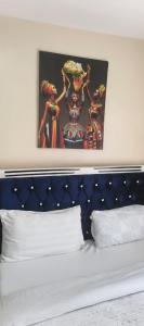 a bed with a blue headboard and a painting above it at STADEVIEW MODERN STUDIOs in Gatunga