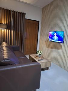 a living room with a couch and a tv on a wall at Ndalem Livtuhayu in Godean