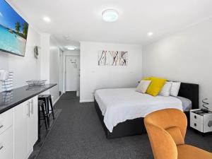 a bedroom with a bed with yellow pillows at Charming Studio Apartment in Mandurah in Mandurah