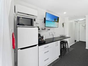 a white kitchen with a refrigerator and a counter at Charming Studio Apartment in Mandurah in Mandurah