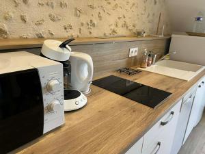 a kitchen counter with a microwave and a sink at Séjour à la campagne - Logement cosy et chaleureux in Courgains