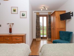 a bedroom with two beds and a blue chair at Swallows Reach in Totnes