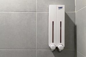 a white soap dispenser on a tiled wall at Mybed Sathorn Hotel in Bangkok +40 photos