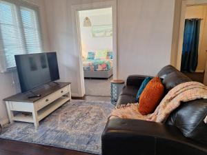 a living room with a leather couch and a flat screen tv at South Bunbury Beach Shack in Bunbury
