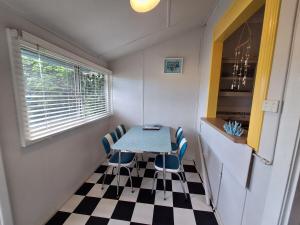 a small kitchen with a table and chairs on a checkered floor at South Bunbury Beach Shack in Bunbury