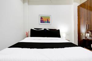 a bedroom with a white bed with black pillows at Hotel O BGPG House in Varanasi