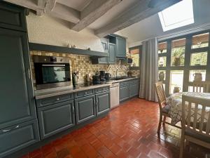 a kitchen with blue cabinets and a television and a table at Gite Des Vignes in Verdigny