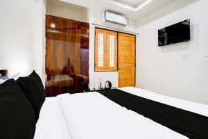 a bedroom with a white bed and a television at Hotel O BGPG House in Varanasi