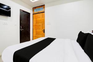 a bedroom with a white bed and a wooden door at Hotel O BGPG House in Varanasi