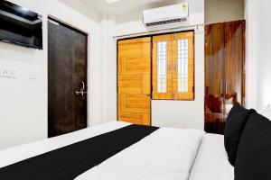 a bedroom with a bed and a television and a door at Hotel O BGPG House in Varanasi +43 photos