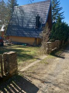 a house with a black roof and a stone fence at jezerski dragulj in Lazići