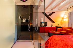 a bedroom with a glass shower and a red bed at Le B. Suites, Chambres & Restaurant in Riquewihr