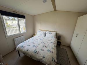 a small bedroom with a bed with a comforter and a window at Captain's Cabin - Brixham - with designated parking in Brixham